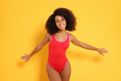 Photo of Beautiful woman in bright one-piece summer swimsuit on yellow background