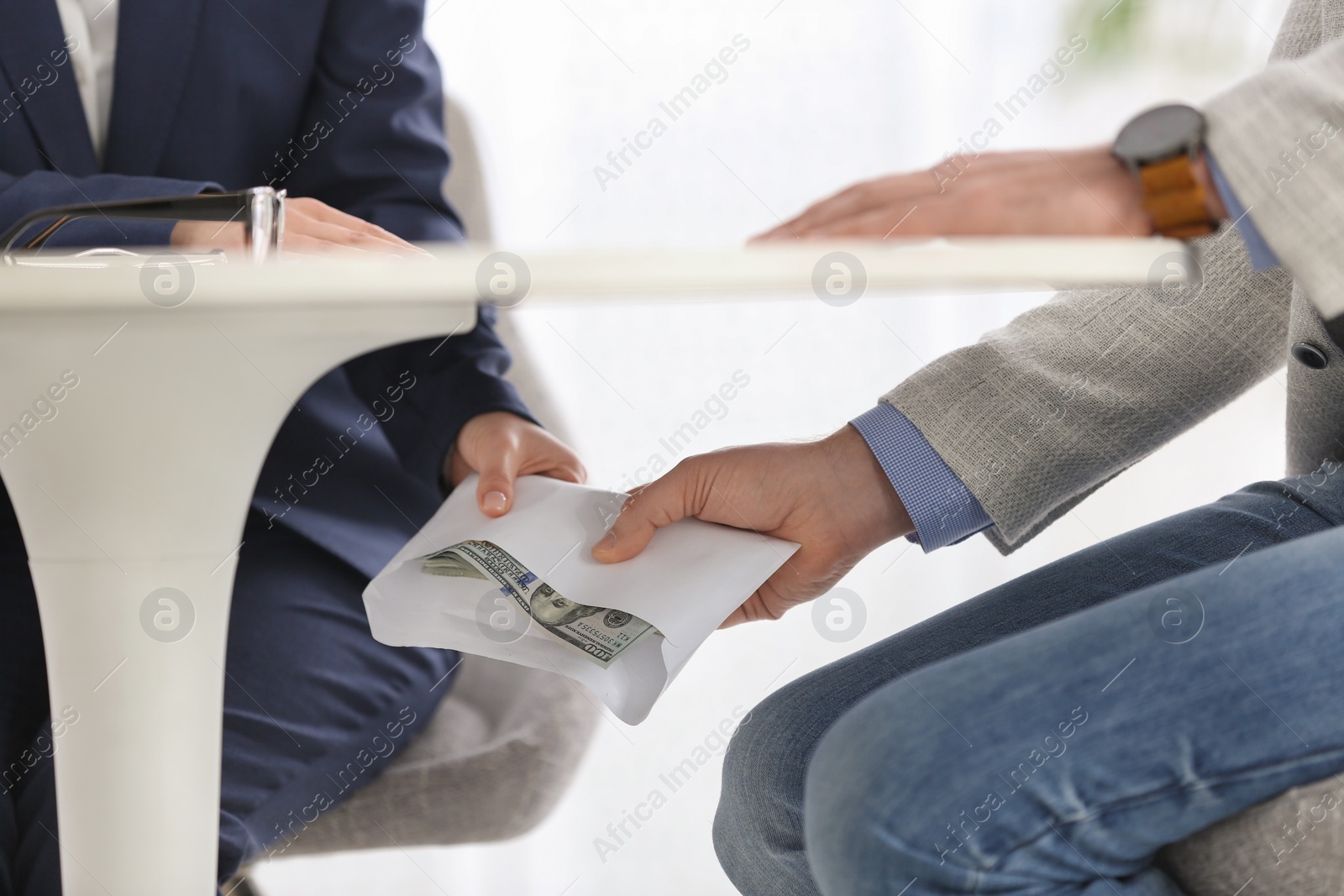 Photo of Man giving bribe to woman under table in office, closeup