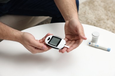 Diabetes test. Man with glucometer at table, closeup