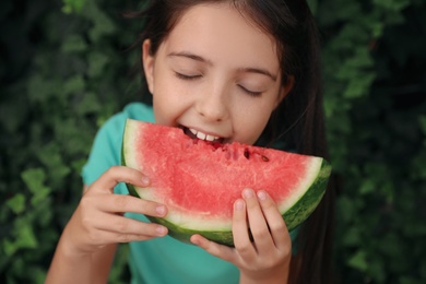 Photo of Cute little girl eating watermelon outdoors on sunny day, closeup