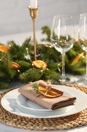 Festive place setting with beautiful dishware, fabric napkin and dried orange slice for Christmas dinner on white table