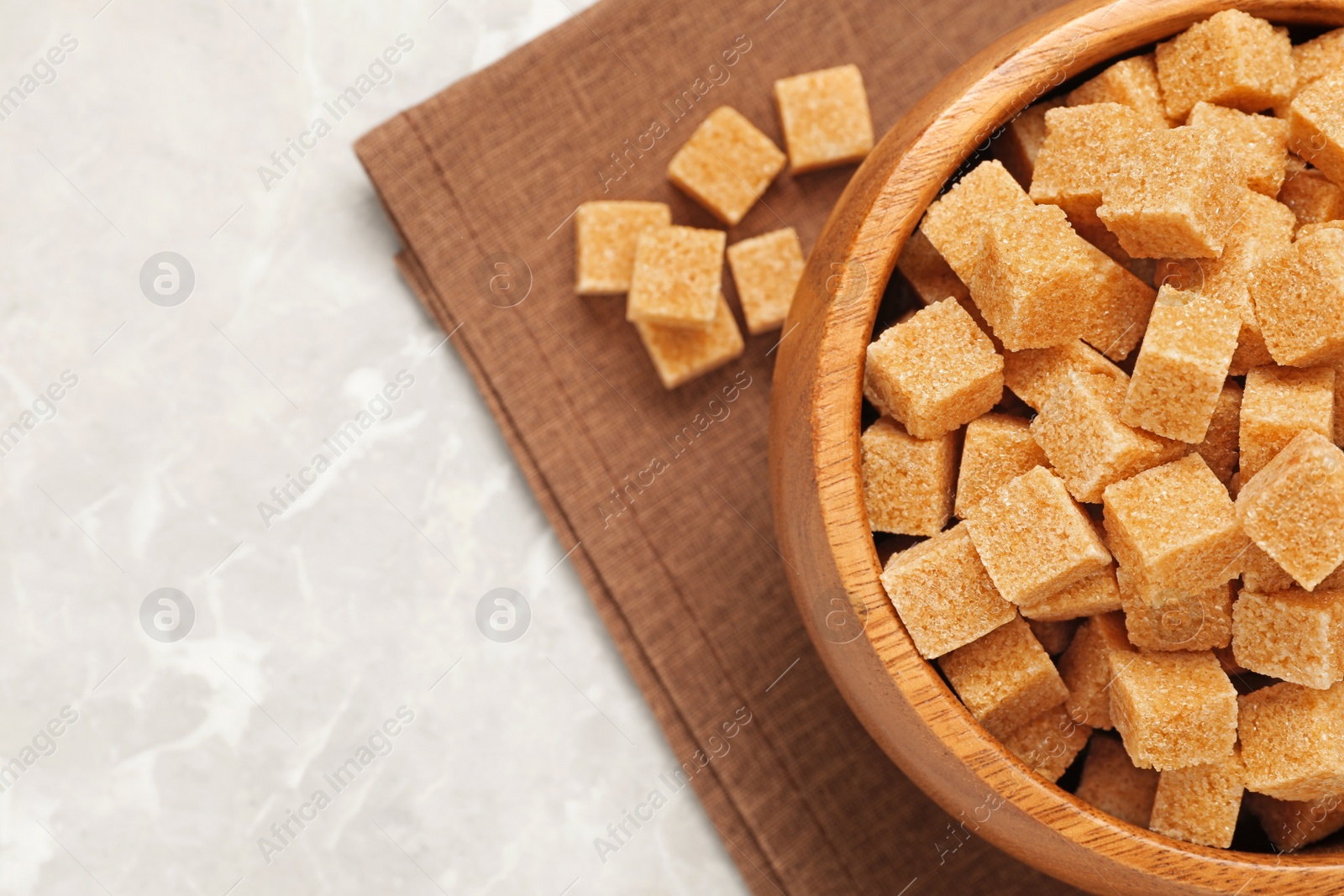 Photo of Brown sugar cubes on light grey marble table, flat lay. Space for text