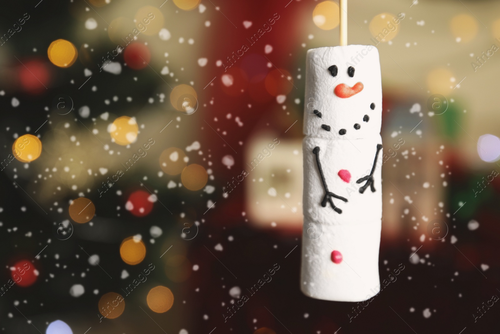 Photo of Funny snowman made of marshmallows against blurred Christmas tree, closeup. Space for text