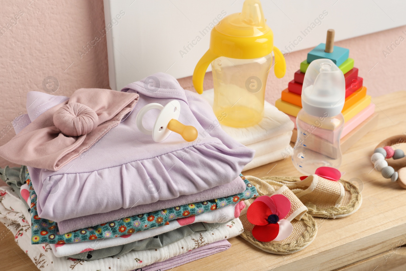 Photo of Baby clothes, toys and accessories on wooden table