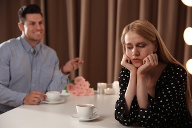Young woman getting bored during first date with overtalkative man in restaurant