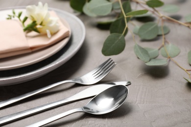 Festive table setting with plates, cutlery and napkin on grey background, closeup