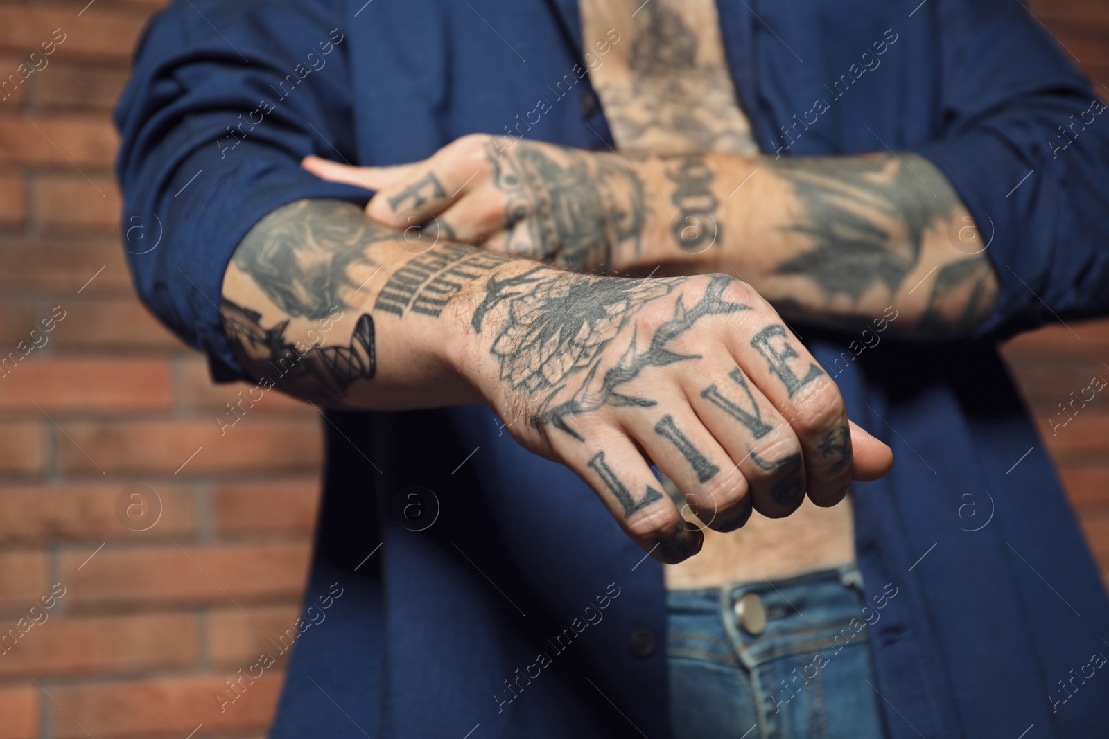 Photo of Young man with tattoos on body near brick wall, closeup