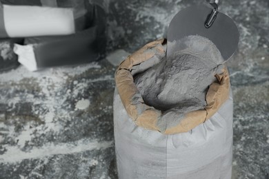 Photo of Cement powder and trowel put in bag on stone floor. Space for text