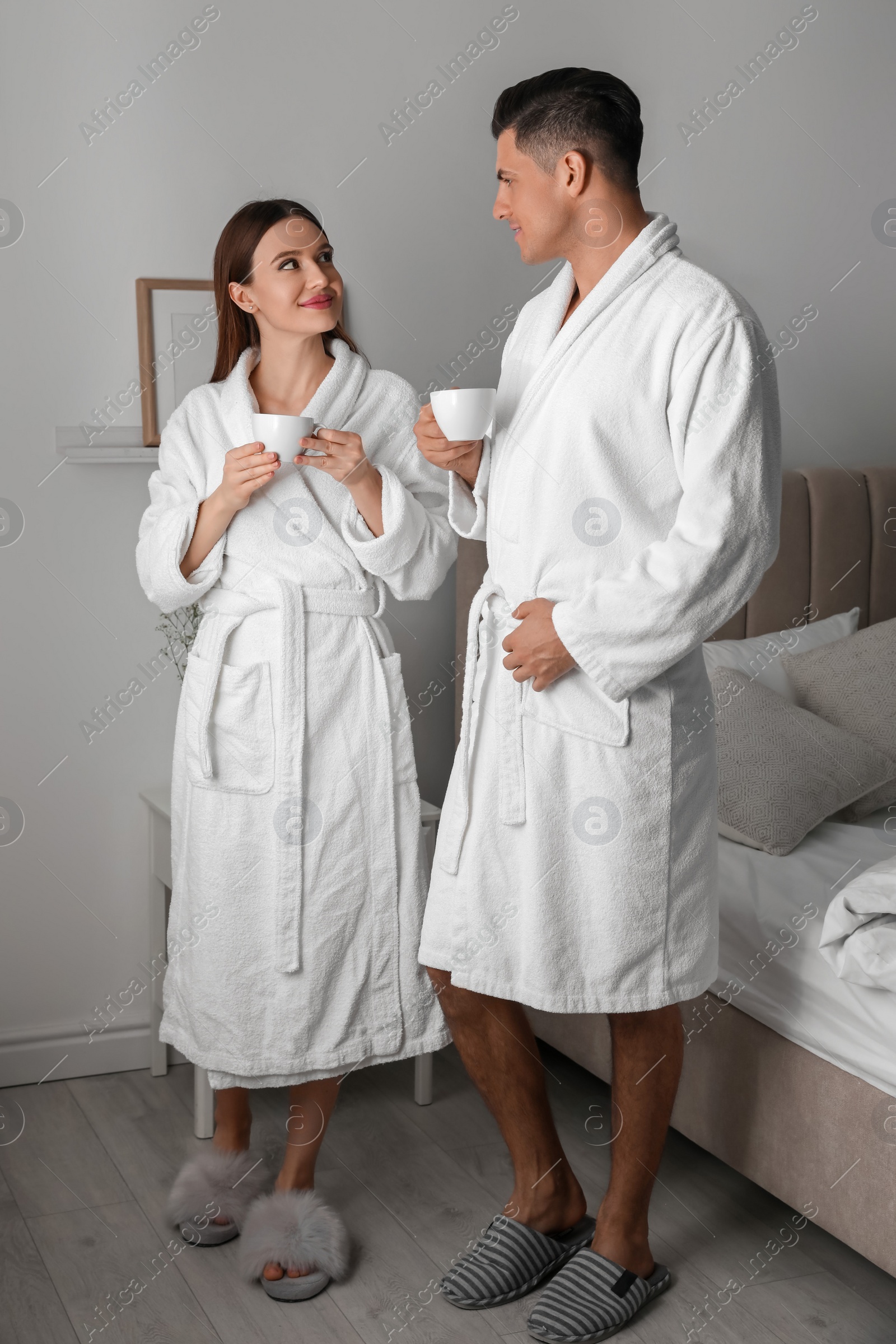 Photo of Happy couple in bathrobes with coffee at home