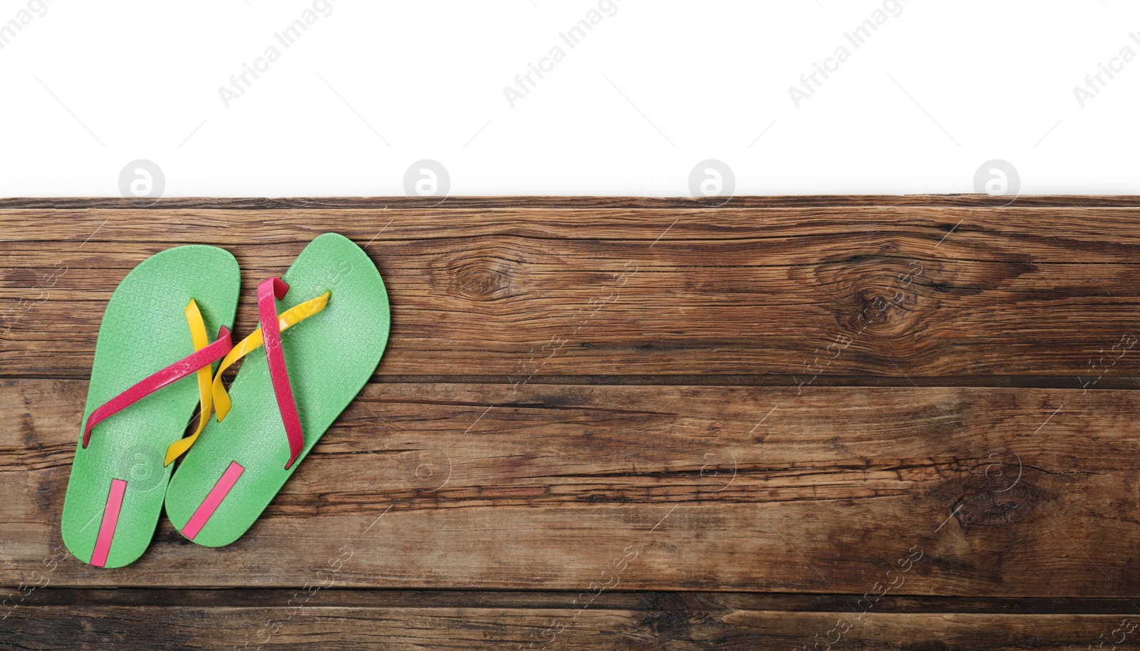Photo of Green flip flops and space for text on wooden table against white background, top view