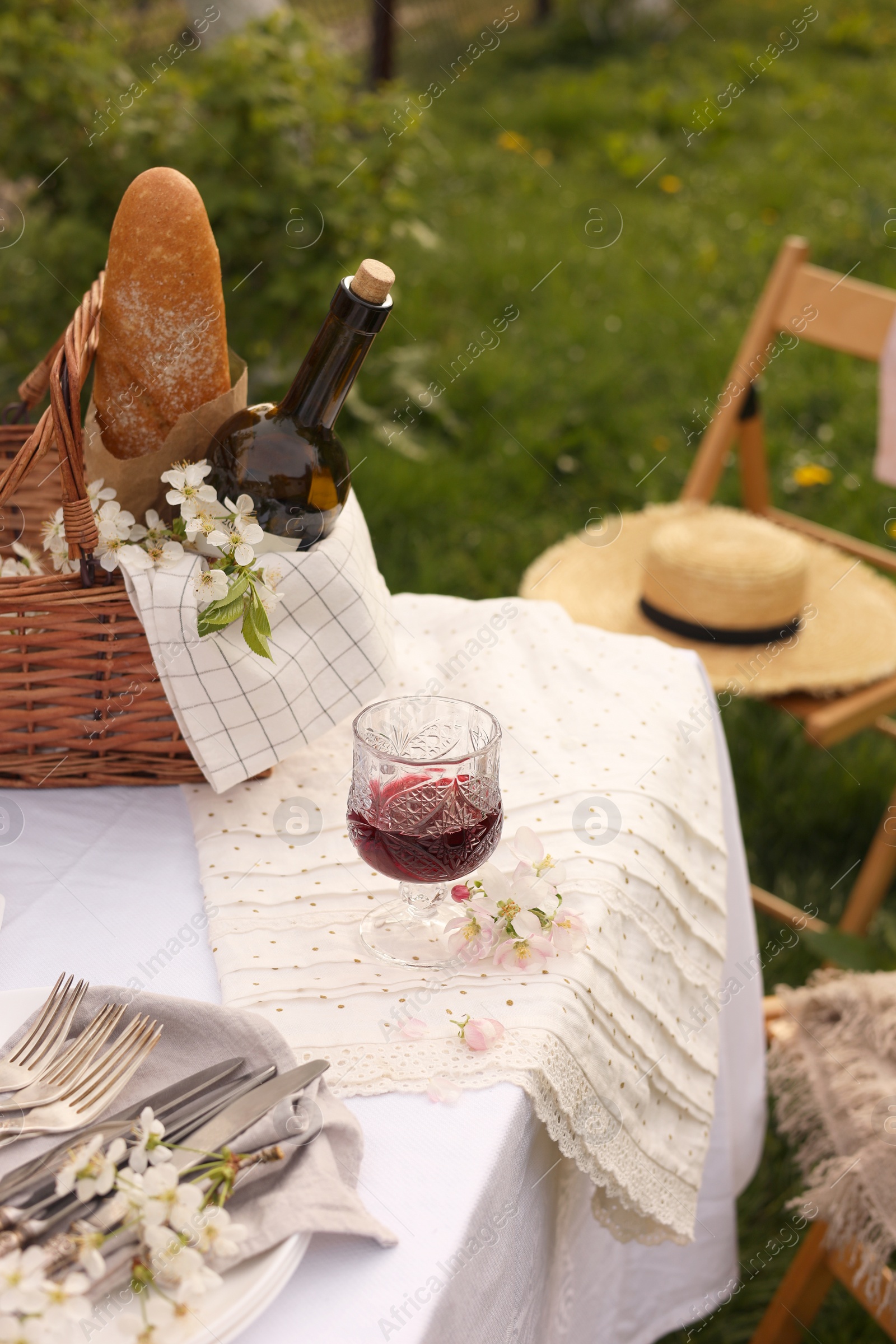 Stylish table setting with beautiful spring flowers and wine in garden Photo of Stylish table setting with beautiful spring flowers and wine in garden