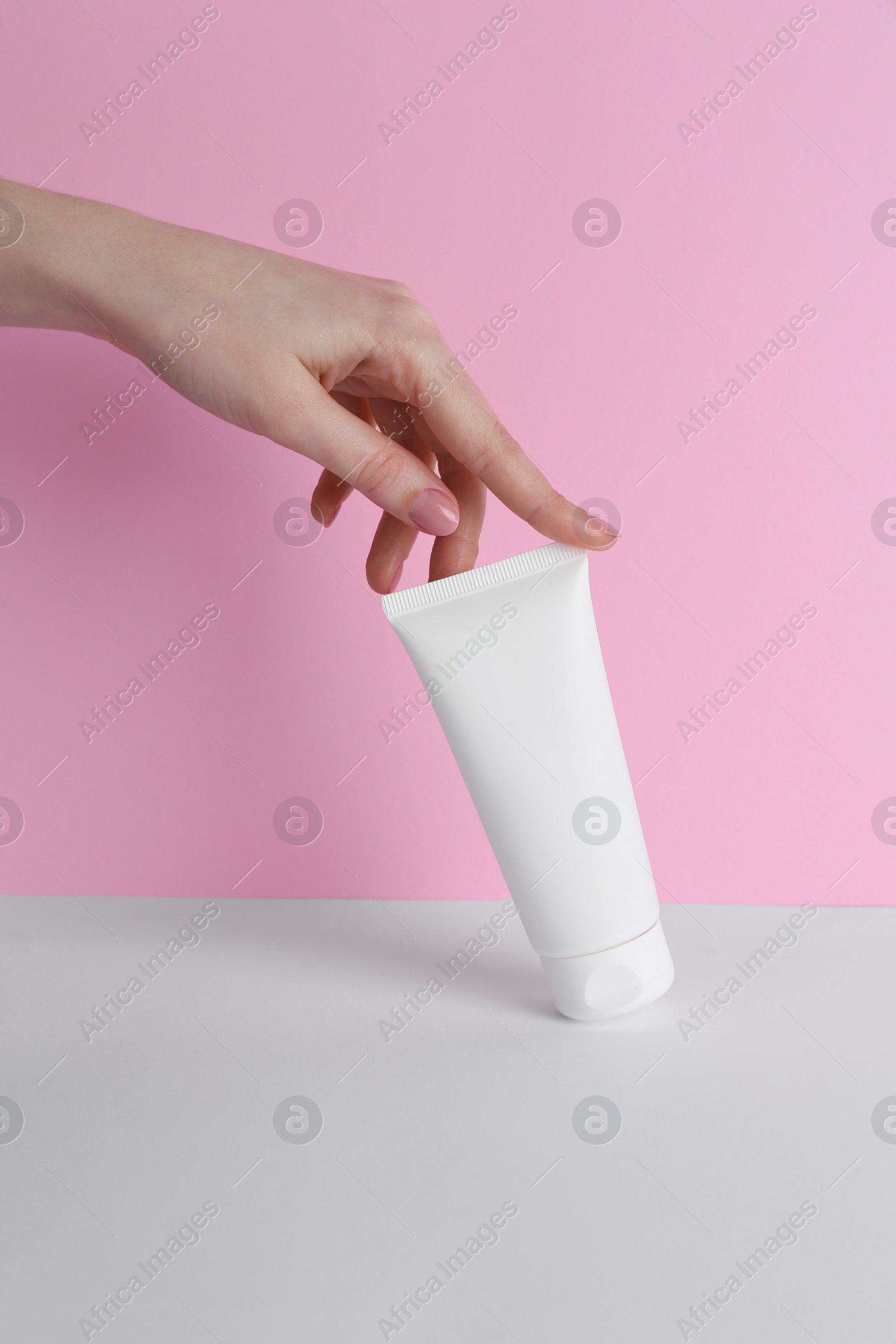 Photo of Woman with tube of cream on color background, closeup