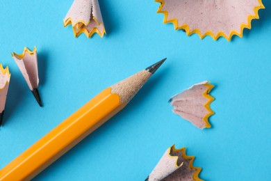 Photo of Graphite pencil and shavings on light blue background, top view. Macro photo