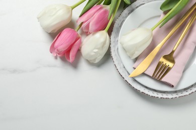 Photo of Stylish table setting with cutlery and tulips on white marble background, flat lay. Space for text