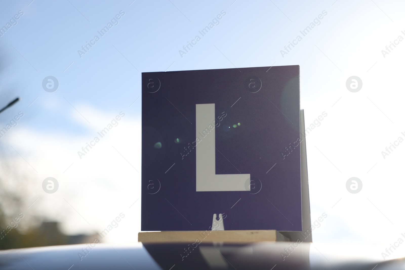 Photo of L-plate on car roof outdoors. Driving school