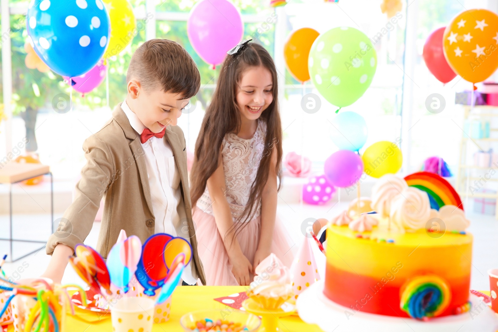 Photo of Cute children near table with treats at birthday party indoors