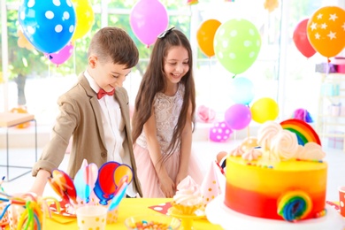 Cute children near table with treats at birthday party indoors