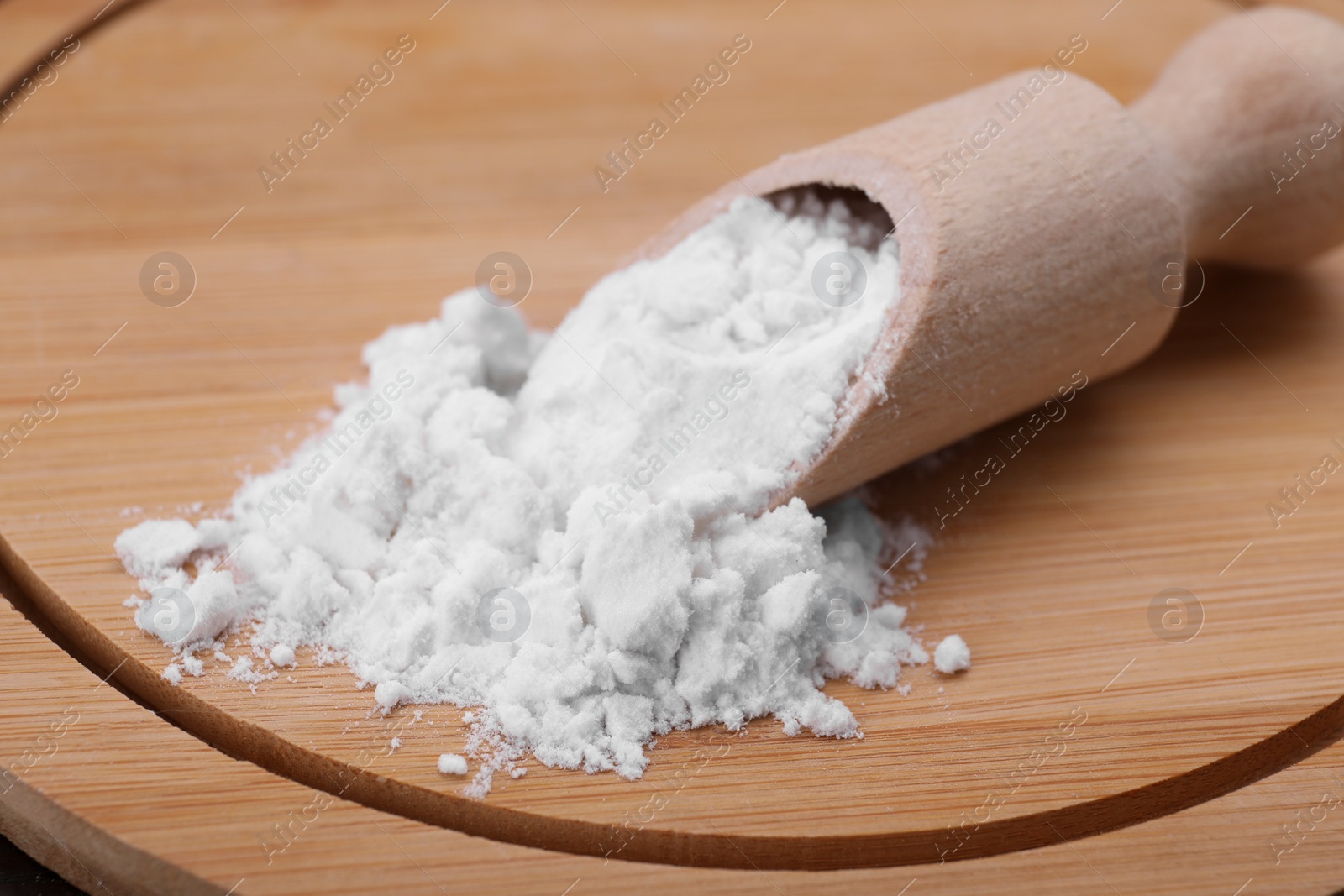 Photo of Wooden scoop with starch on board, closeup