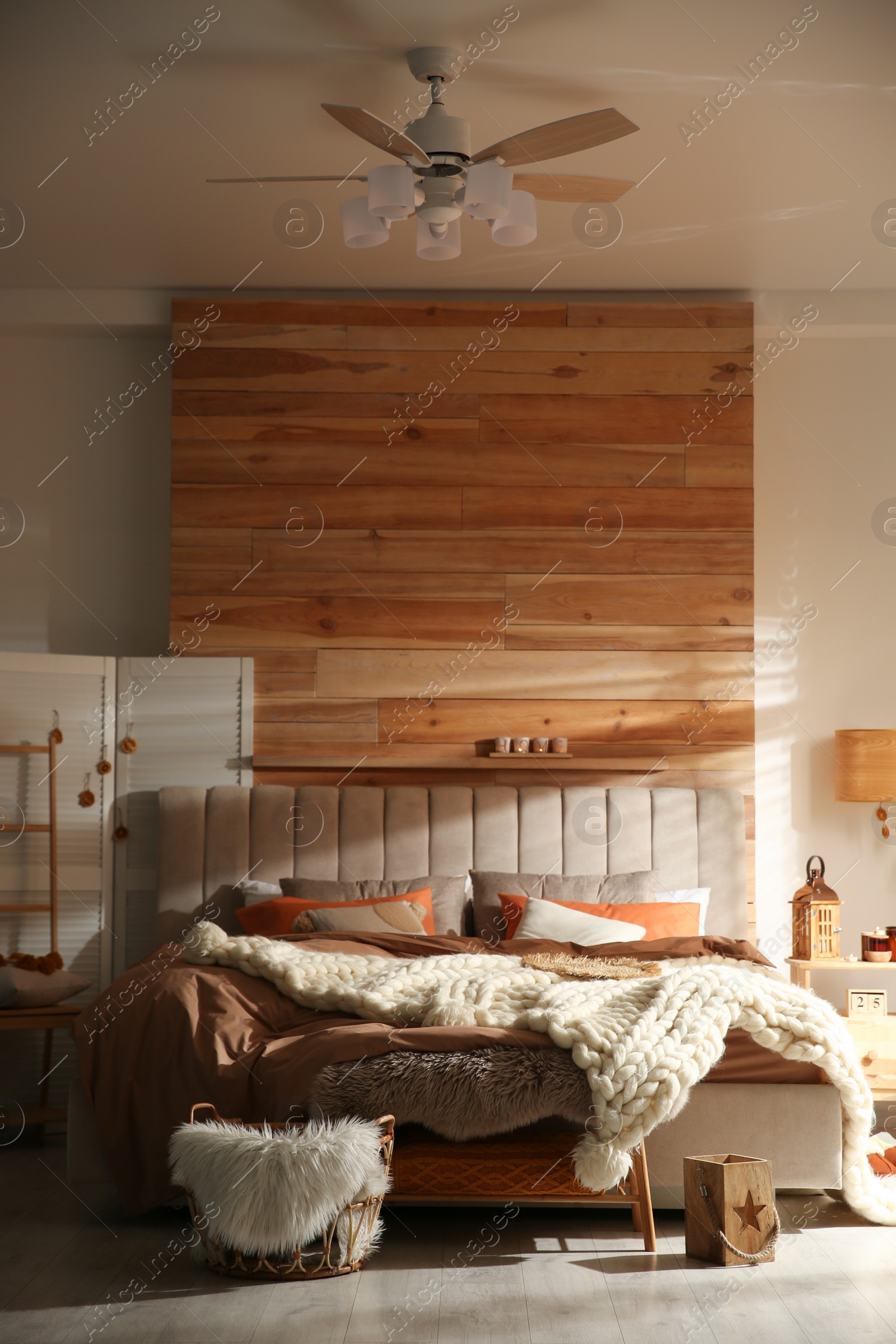 Photo of Cozy bedroom interior with knitted blanket and cushions