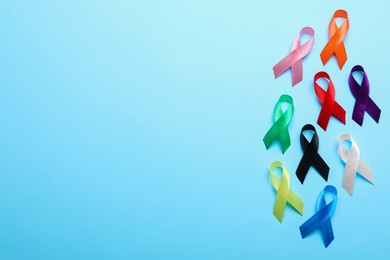 Colorful ribbons on light blue background, flat lay with space for text. World Cancer Day