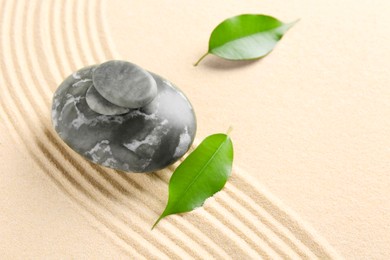 Photo of Zen garden stones and leaves on beige sand with pattern