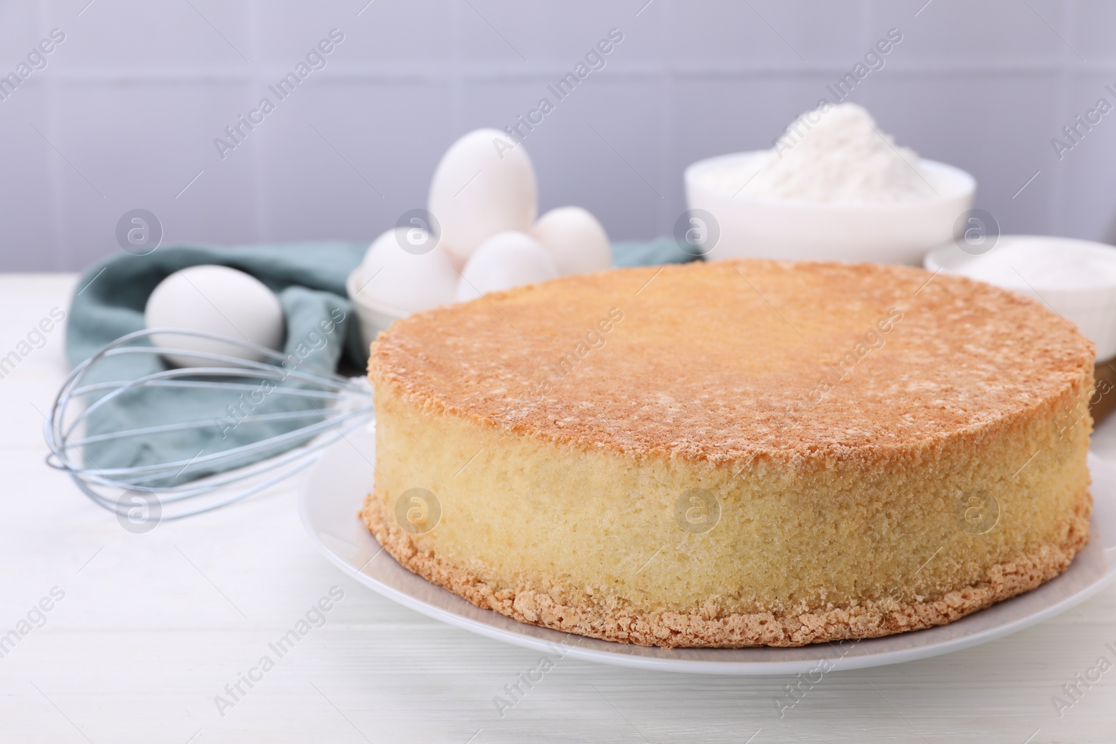 Photo of Plate with delicious sponge cake on white wooden table, closeup