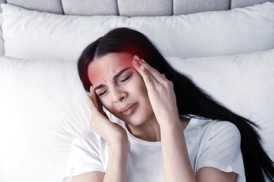 Image of Young woman suffering from migraine in bed, above view