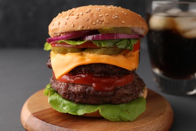 Photo of Tasty cheeseburger with patties and tomato on grey table, closeup