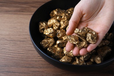 Photo of Woman with gold nuggets at wooden table, closeup