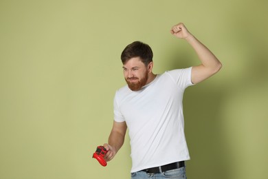 Young man with game controller on pale green background. Space for text