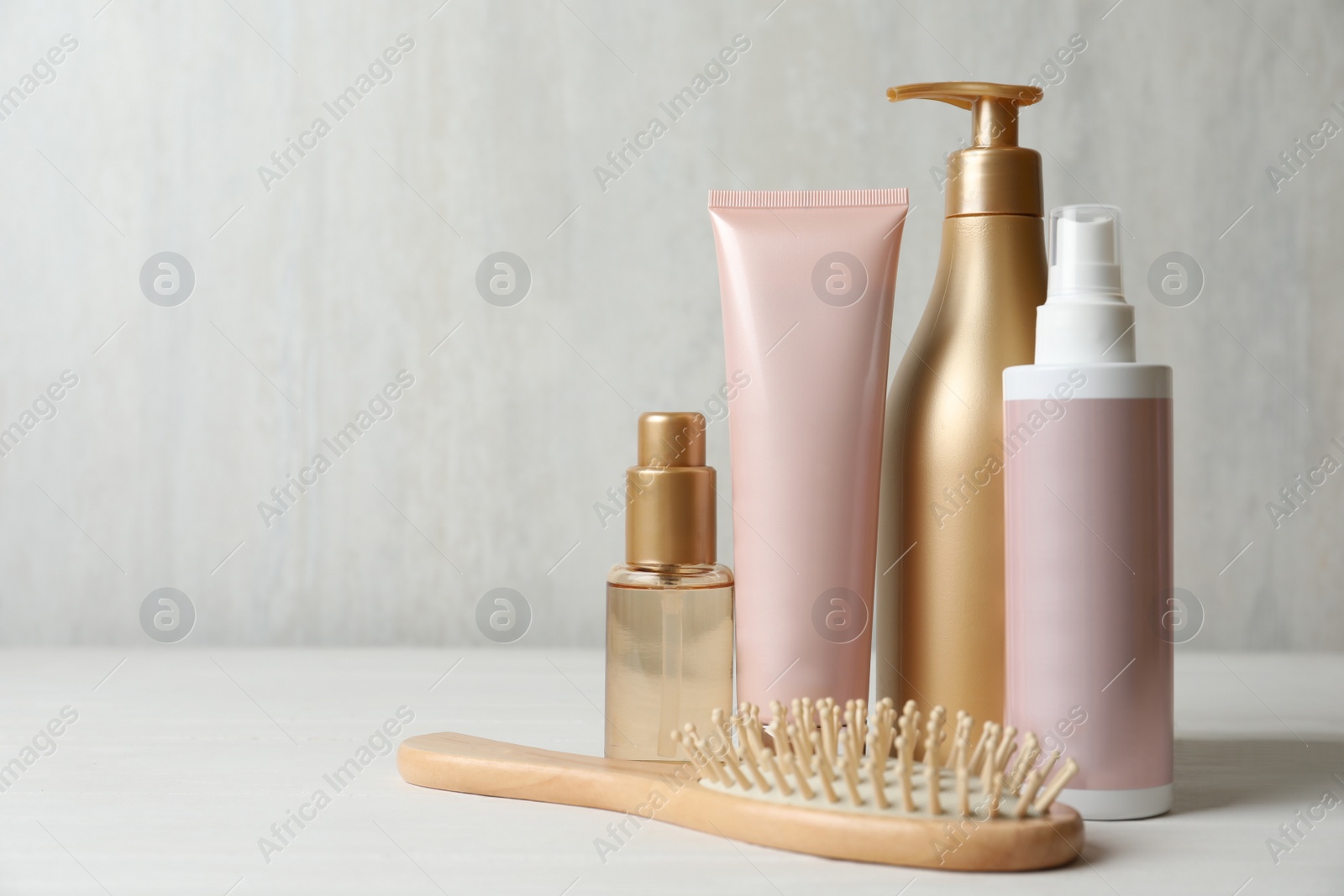 Photo of Different hair products and brush on white wooden table. Space for text