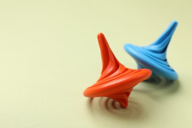 Photo of Red and blue spinning tops on green background, closeup. Space for text