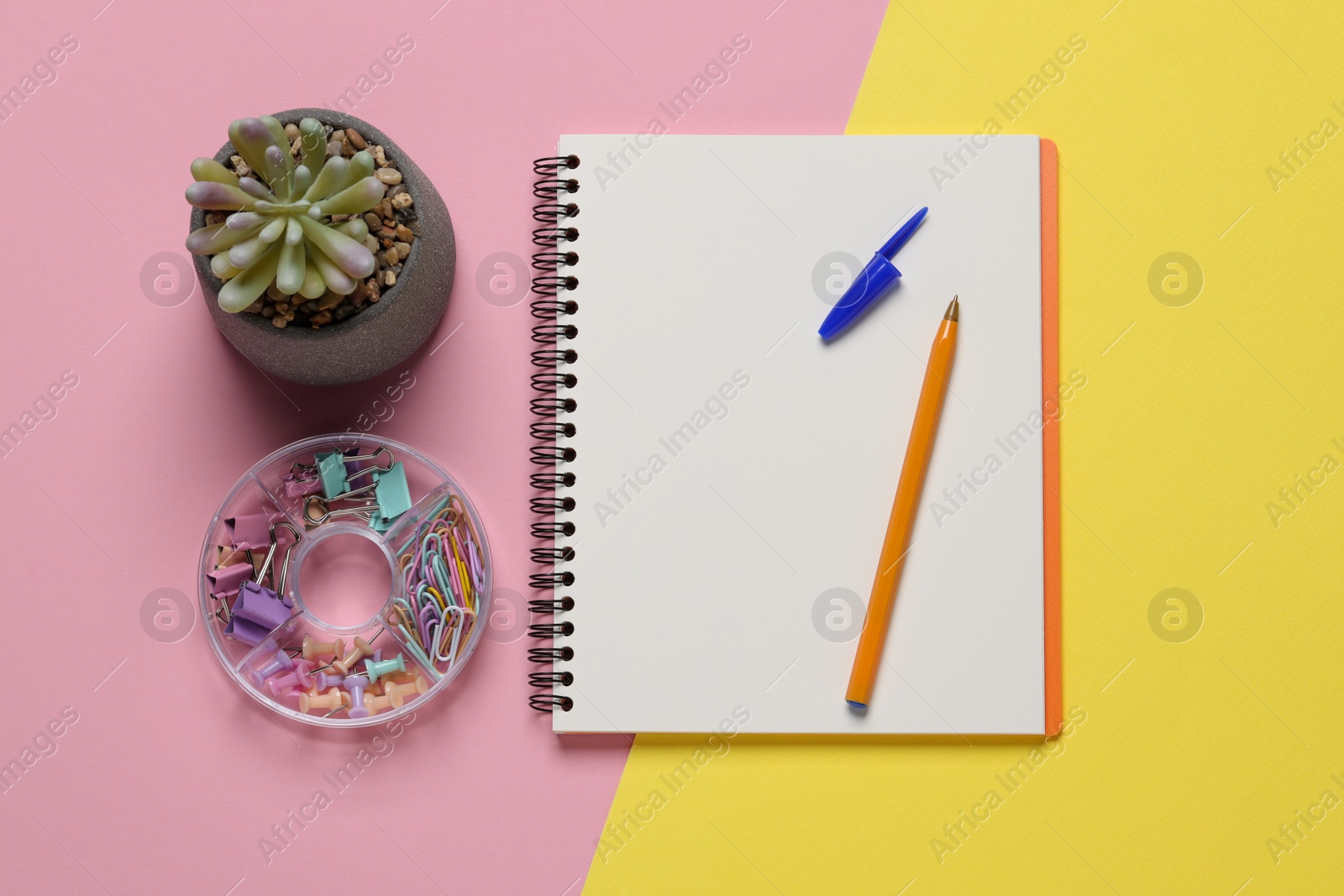 Photo of Ballpoint pen, notebook and different clips on color background, flat lay