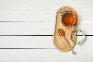 Jar of honey and dipper on white wooden table, top view. Space for text