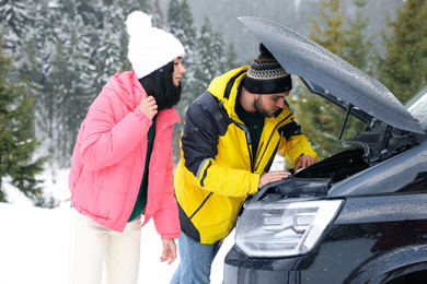 Photo of Stressed couple near broken car outdoors on winter day
