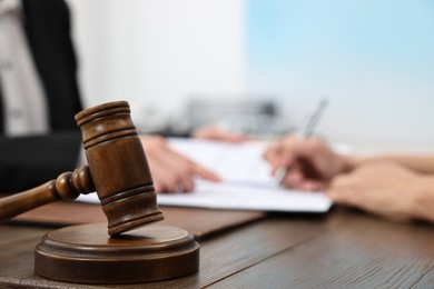 Photo of Senior woman signing document in lawyer's office, focus on gavel