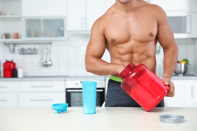 Photo of Young athletic man preparing protein shake in kitchen, closeup view. Space for text