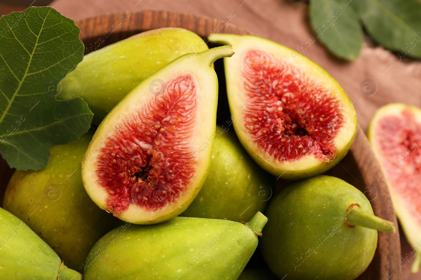 Photo of Cut and whole green figs on table, closeup