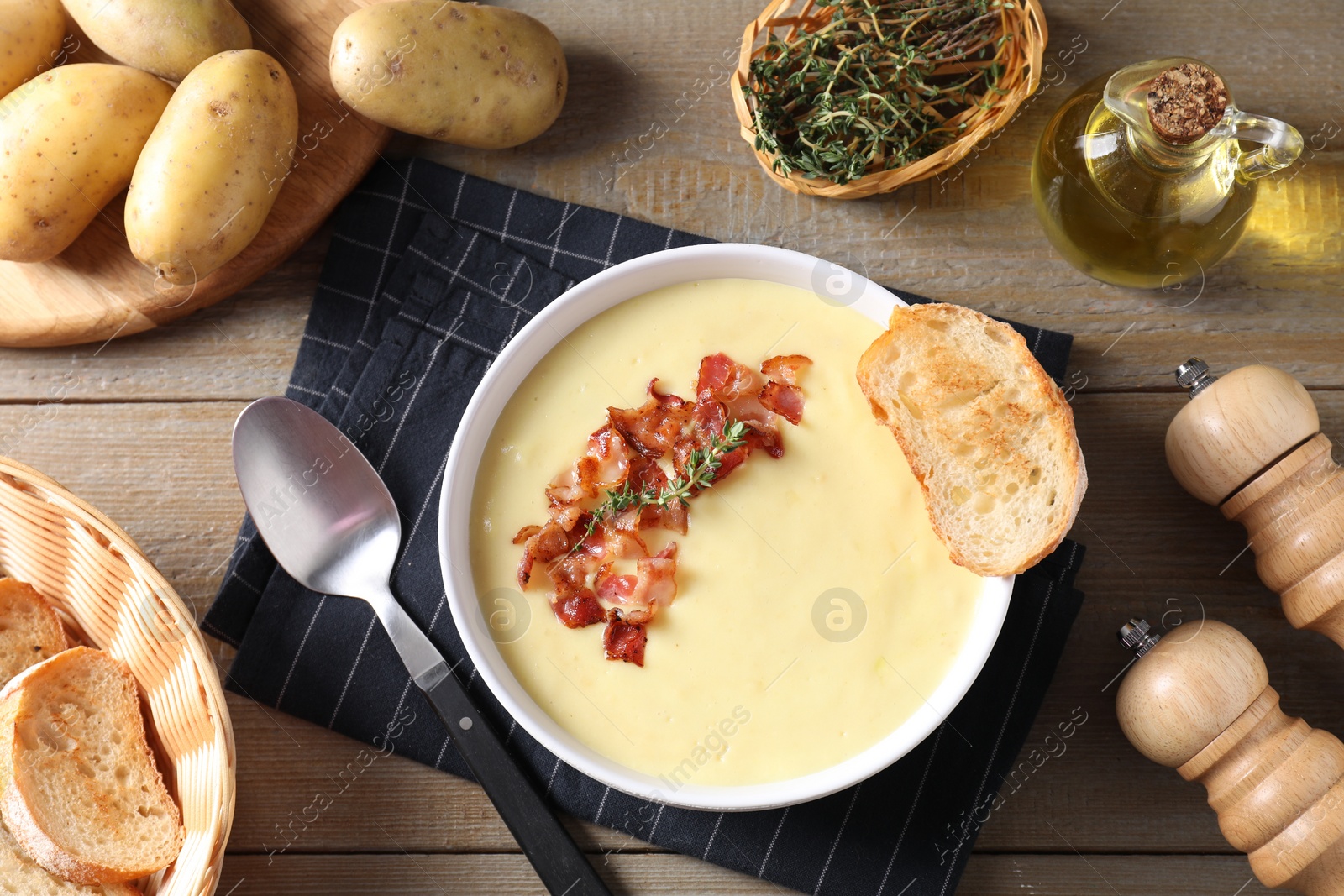 Photo of Tasty potato soup with bacon in bowl served on wooden table, flat lay