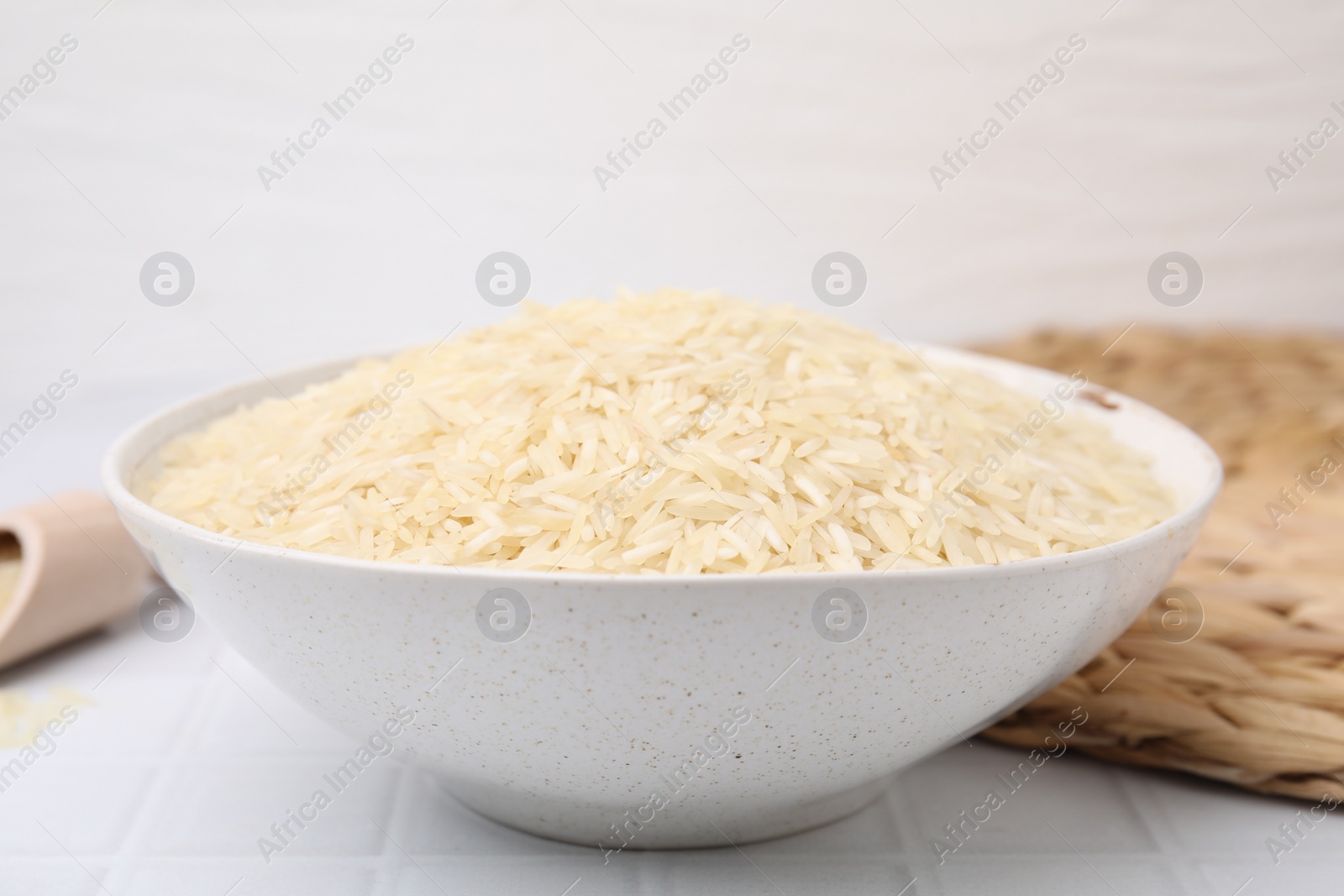 Photo of Raw rice in bowl on white table, closeup