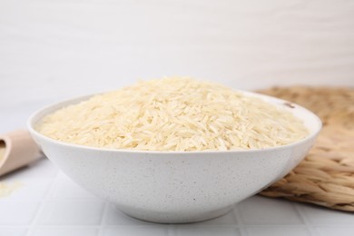 Raw rice in bowl on white table, closeup