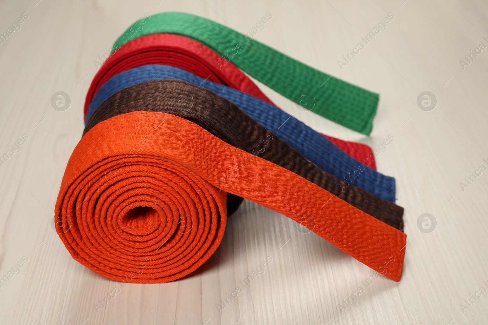 Photo of Colorful karate belts on wooden background, closeup