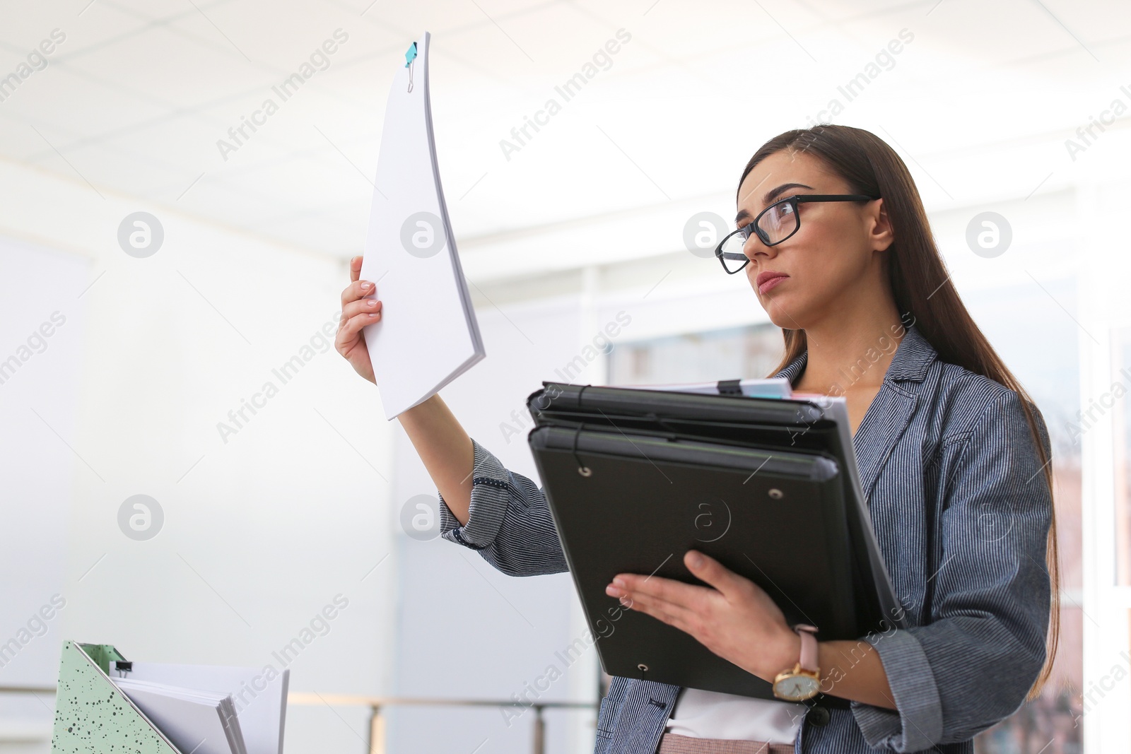 Photo of Young woman working with documents in office