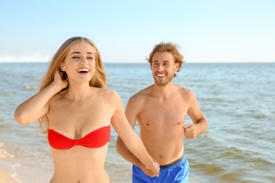 Photo of Happy young couple in beachwear having fun on seashore