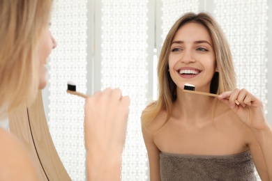 Photo of Woman brushing teeth near mirror in bathroom