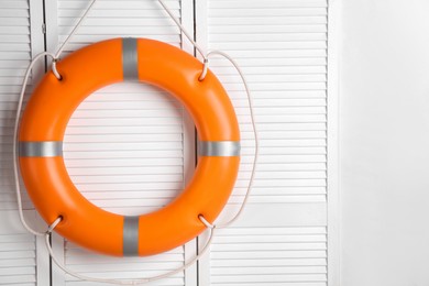Orange lifebuoy on white wooden background, space for text. Rescue equipment