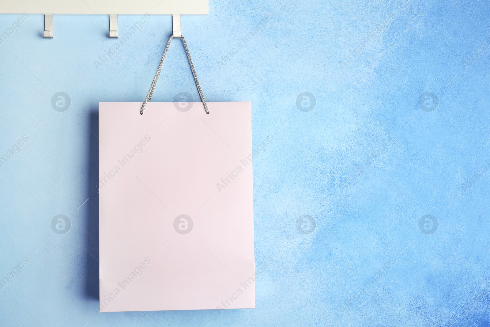 Photo of Rack with paper shopping bag on color wall. Mockup for design