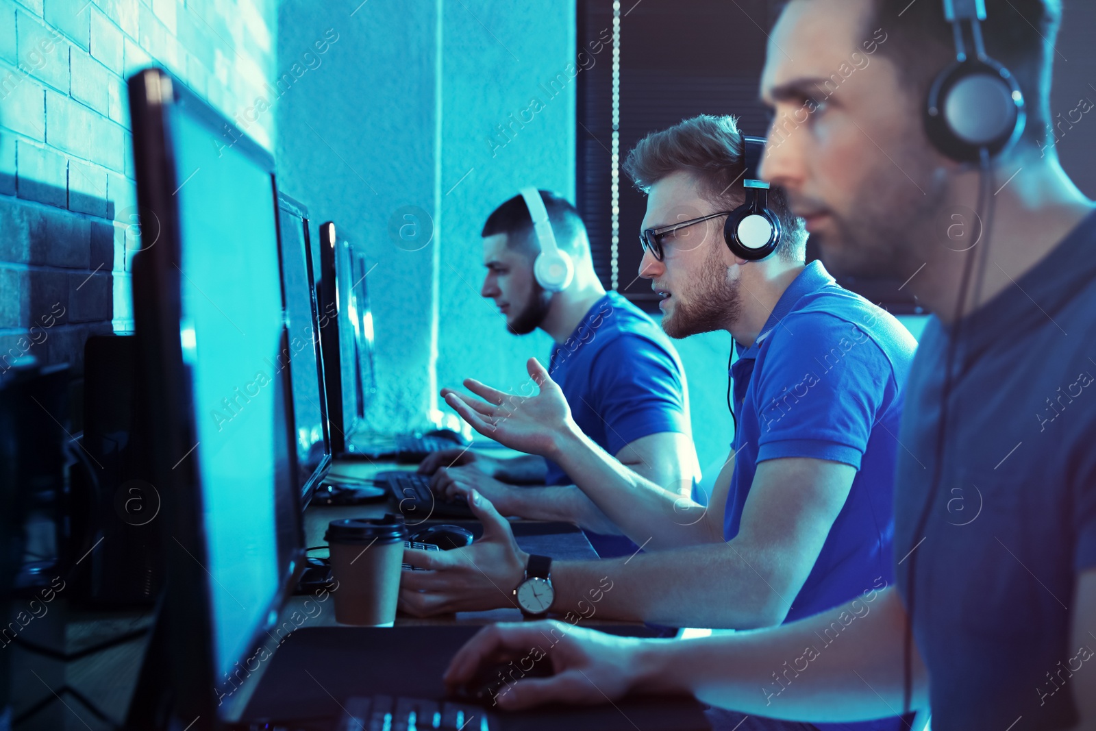 Photo of Group of people playing video games in internet cafe