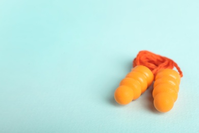 Photo of Pair of orange ear plugs with cord on turquoise background. Space for text
