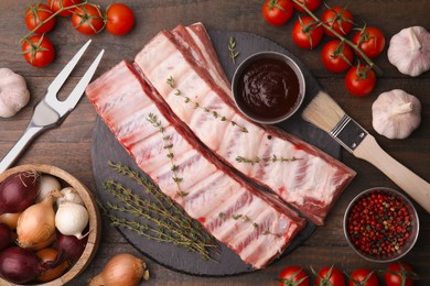 Photo of Flat lay composition with raw pork ribs and sauce on wooden table